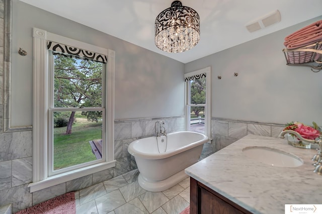 bathroom featuring a wealth of natural light, vanity, tile walls, and a tub