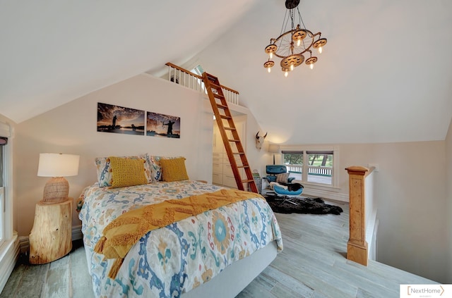 bedroom with hardwood / wood-style floors, a notable chandelier, and lofted ceiling