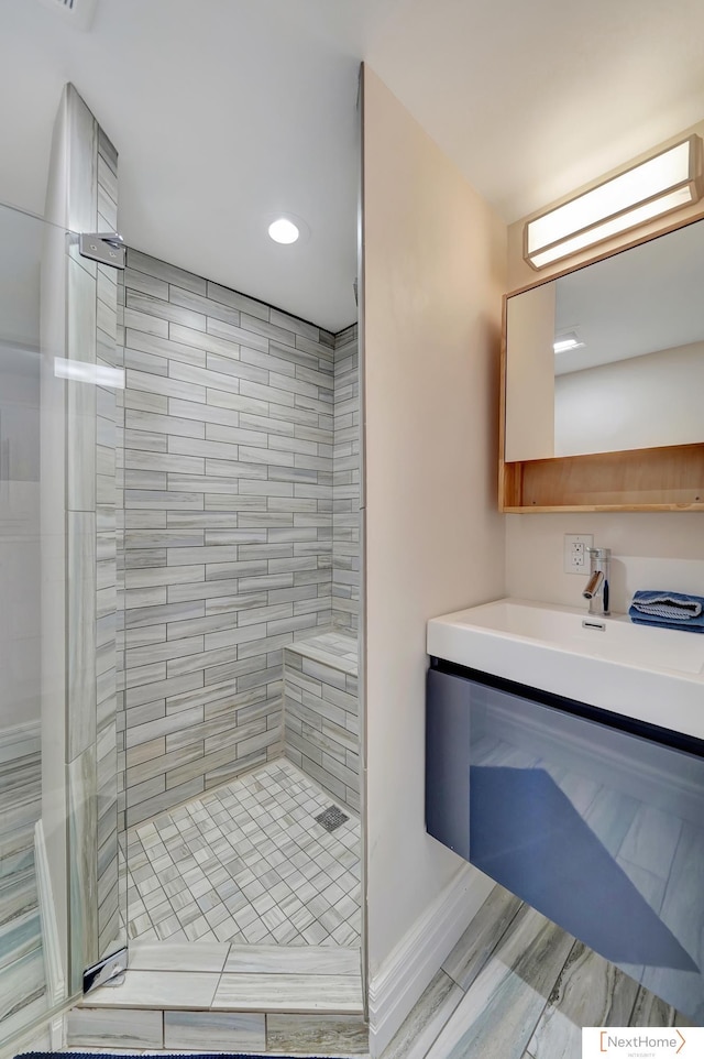 bathroom with a tile shower and vanity