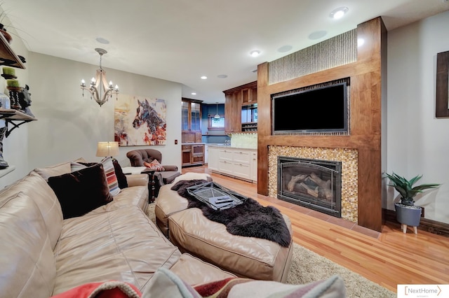 living room with a notable chandelier, light hardwood / wood-style floors, and a fireplace