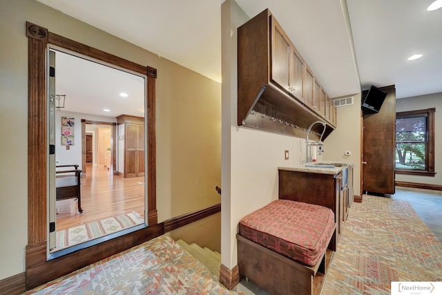 interior space with light hardwood / wood-style floors, light stone counters, and sink