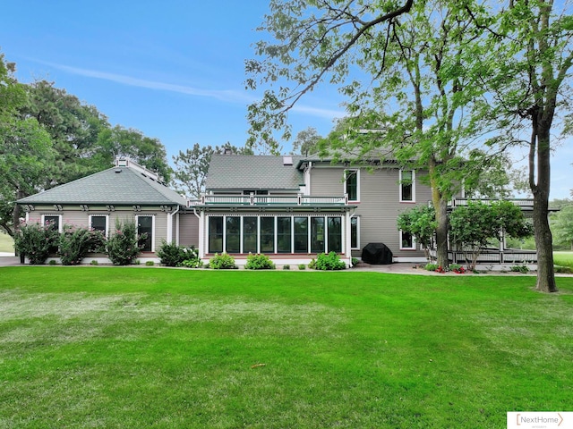 rear view of property featuring a yard and a sunroom