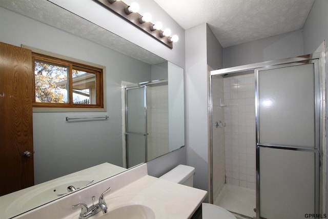 bathroom with vanity, a textured ceiling, toilet, and walk in shower