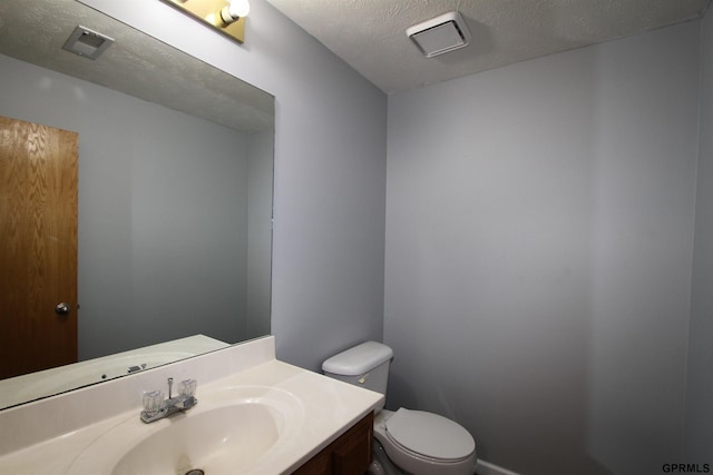 bathroom featuring vanity, a textured ceiling, and toilet