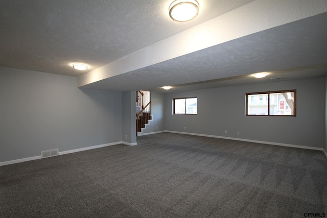 basement with dark carpet and a textured ceiling