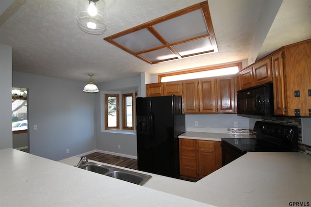 kitchen featuring pendant lighting, black appliances, sink, hardwood / wood-style flooring, and a textured ceiling