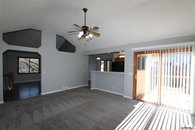 unfurnished living room with dark carpet, ceiling fan, and lofted ceiling