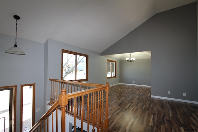 corridor with dark hardwood / wood-style flooring, high vaulted ceiling, and a notable chandelier