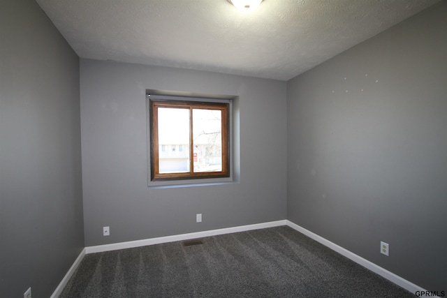 unfurnished room with carpet and a textured ceiling