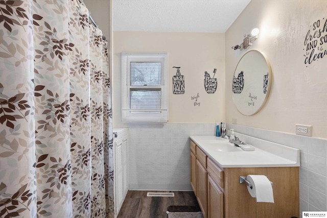 bathroom featuring vanity, a textured ceiling, hardwood / wood-style flooring, and tile walls