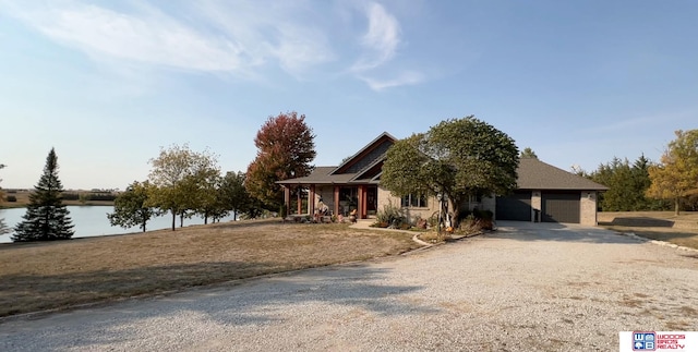 view of front of house with covered porch, a water view, and a garage