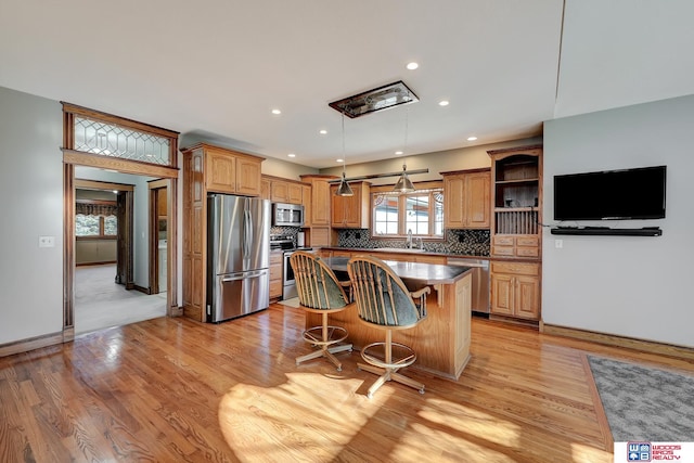 kitchen with appliances with stainless steel finishes, a center island, light hardwood / wood-style flooring, and a kitchen breakfast bar