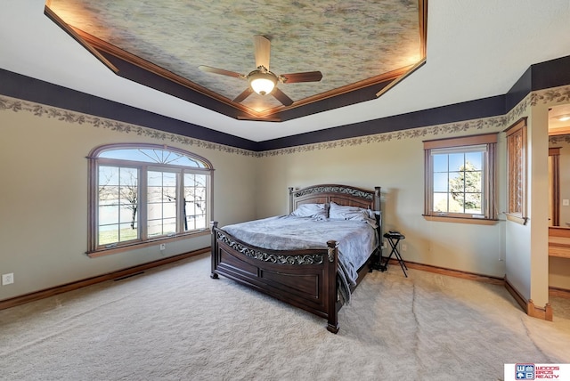 bedroom with light carpet, a tray ceiling, ceiling fan, and crown molding