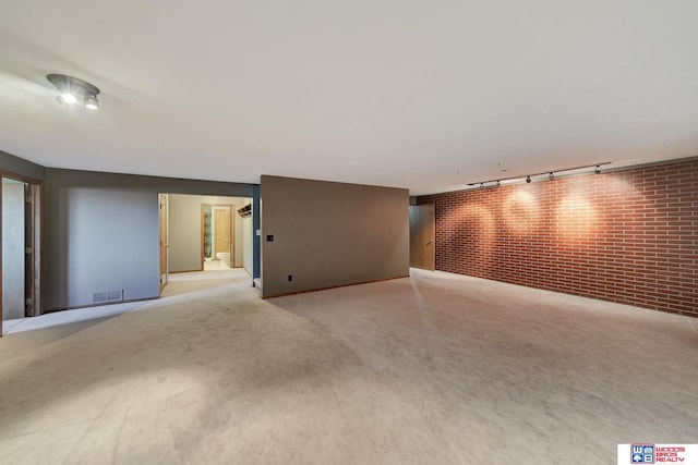 unfurnished room with brick wall and track lighting