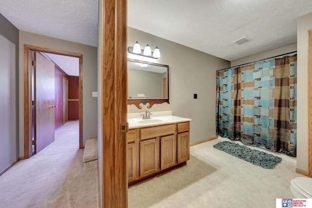 bathroom with vanity, curtained shower, toilet, and a textured ceiling