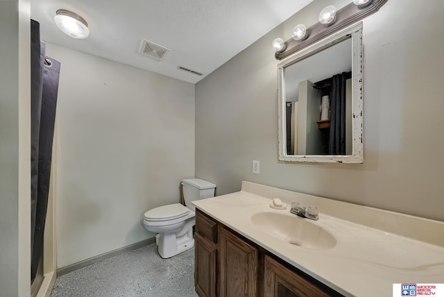 bathroom with a textured ceiling, vanity, toilet, and walk in shower