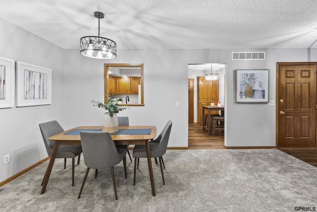 dining room with carpet floors, a textured ceiling, and an inviting chandelier