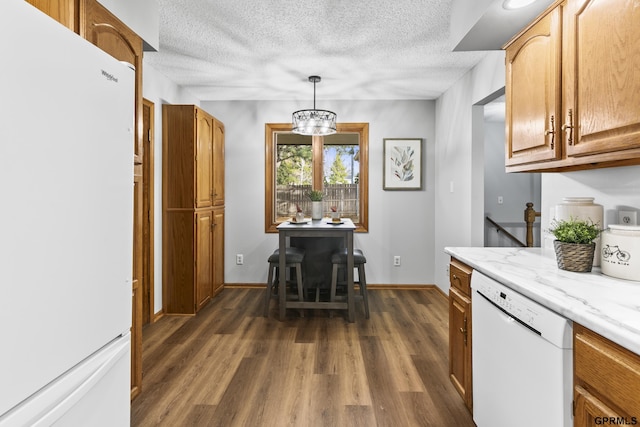 kitchen featuring dark hardwood / wood-style flooring, white appliances, a textured ceiling, pendant lighting, and an inviting chandelier