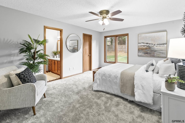 bedroom with a textured ceiling, ensuite bathroom, ceiling fan, and light colored carpet