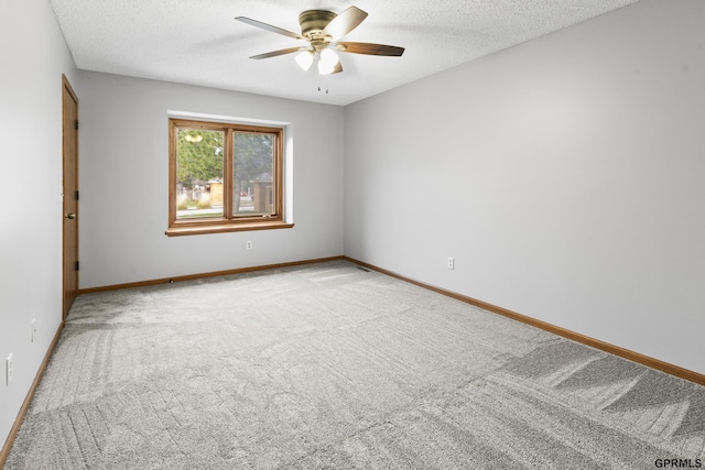 spare room with a textured ceiling, light colored carpet, and ceiling fan