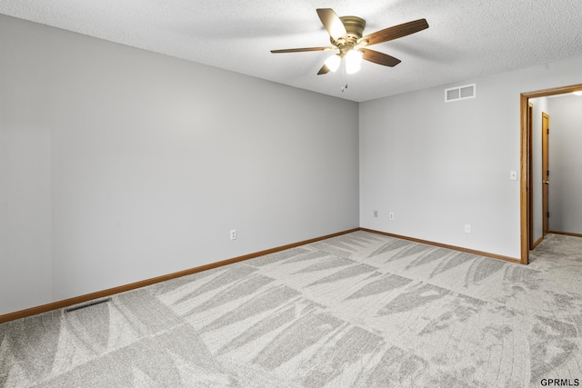 spare room featuring light carpet, ceiling fan, and a textured ceiling