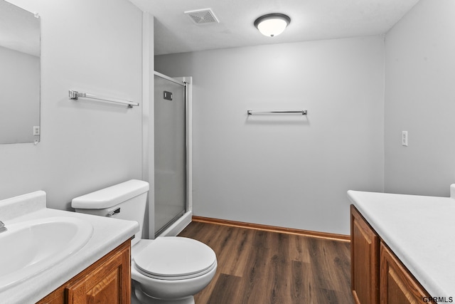 bathroom with vanity, toilet, a shower with shower door, and wood-type flooring