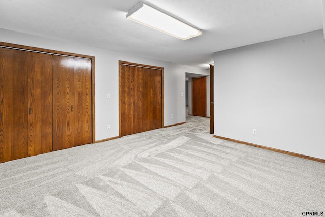 unfurnished bedroom featuring light colored carpet and two closets