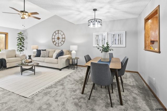 dining area with carpet flooring, ceiling fan with notable chandelier, a textured ceiling, and vaulted ceiling