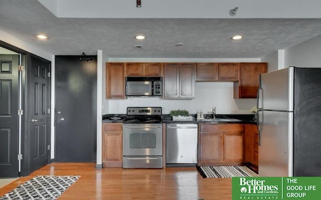 kitchen featuring light hardwood / wood-style flooring, stainless steel appliances, a textured ceiling, and sink