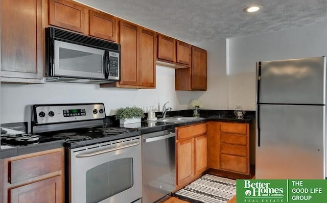 kitchen with appliances with stainless steel finishes, a textured ceiling, and sink