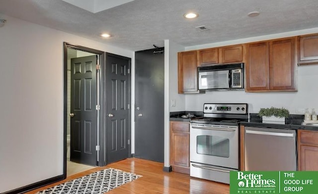 kitchen featuring stainless steel appliances, a textured ceiling, and light wood-type flooring