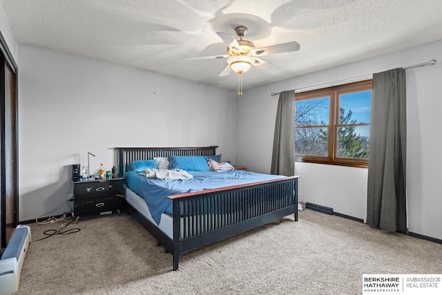 bedroom featuring ceiling fan, light carpet, and a textured ceiling