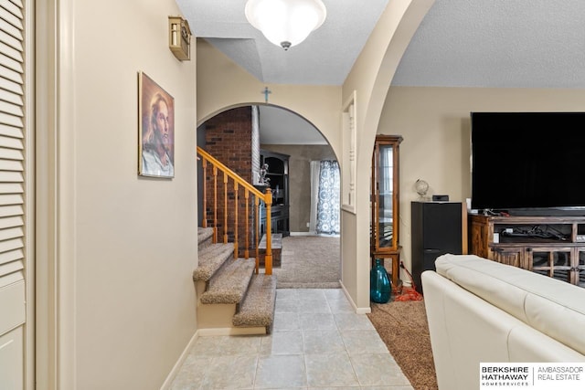 foyer entrance featuring a textured ceiling and light colored carpet