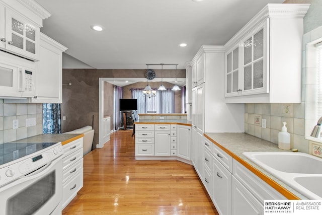 kitchen with hanging light fixtures, an inviting chandelier, white appliances, white cabinets, and light wood-type flooring