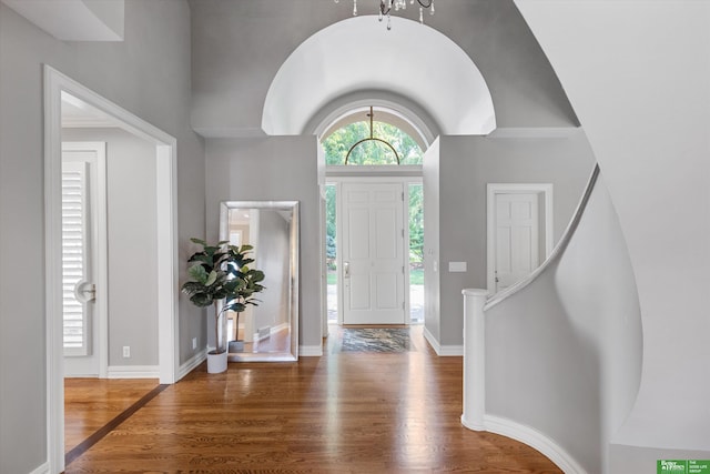 foyer entrance with dark hardwood / wood-style floors, a towering ceiling, and a chandelier