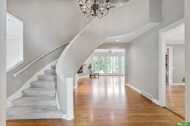 stairs featuring hardwood / wood-style flooring and ceiling fan with notable chandelier