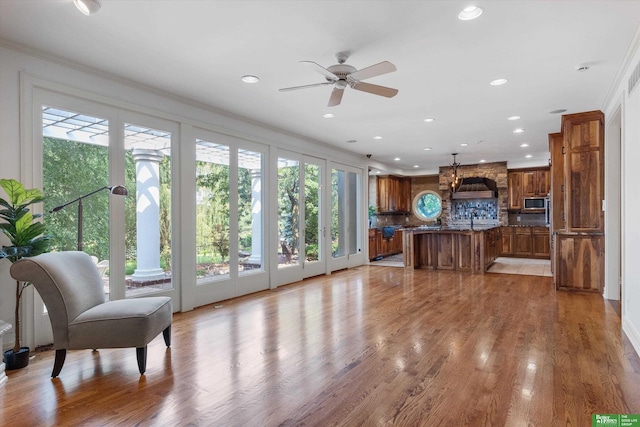 living room with light wood-type flooring, plenty of natural light, and ornamental molding