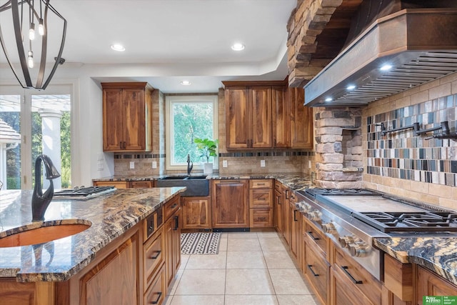 kitchen with custom range hood, tasteful backsplash, a healthy amount of sunlight, and sink