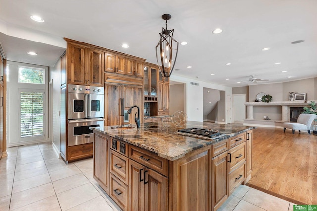 kitchen featuring light tile patterned floors, stainless steel appliances, decorative light fixtures, and dark stone counters