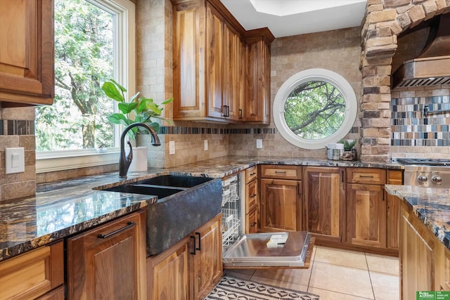 kitchen with tasteful backsplash, dark stone countertops, a wealth of natural light, and light tile patterned flooring