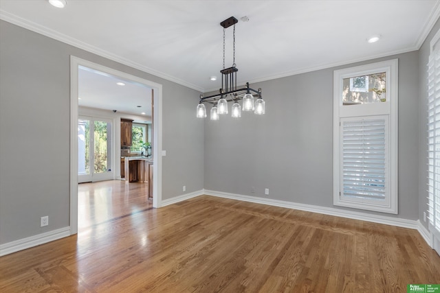 unfurnished dining area featuring hardwood / wood-style flooring, ornamental molding, and a chandelier