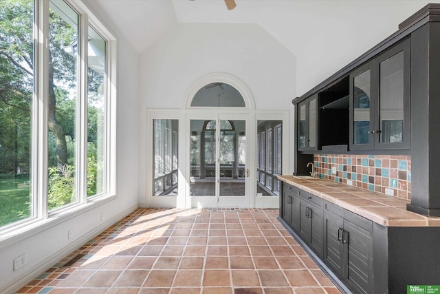 unfurnished sunroom with ceiling fan, sink, and lofted ceiling