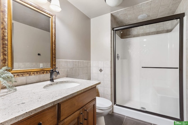 bathroom featuring tile patterned flooring, toilet, a shower with door, and tile walls