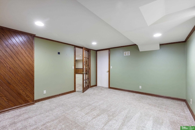 basement featuring light colored carpet, crown molding, and wood walls