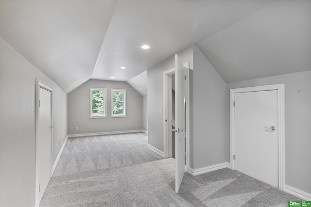 additional living space featuring light colored carpet and vaulted ceiling