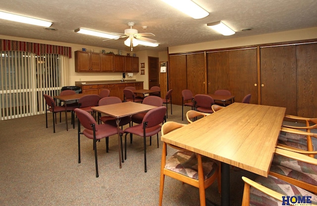 dining space with ceiling fan, carpet floors, and a textured ceiling