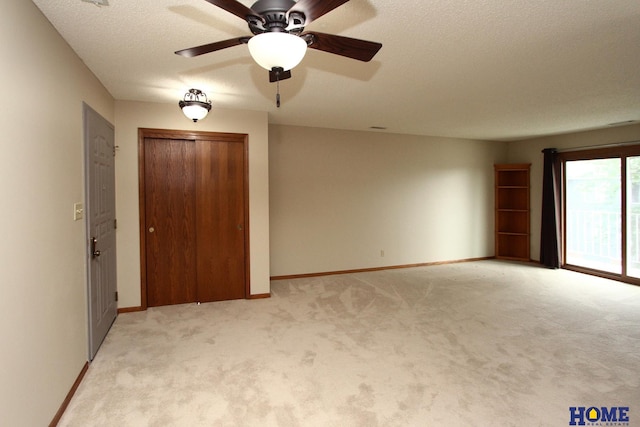 unfurnished bedroom with ceiling fan, light colored carpet, and a textured ceiling