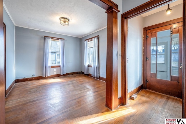 foyer entrance with crown molding, a textured ceiling, and light wood-type flooring