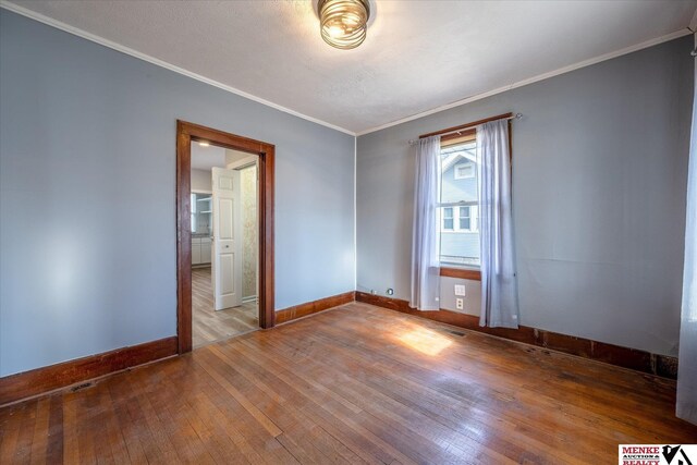 spare room with crown molding, wood-type flooring, and a textured ceiling