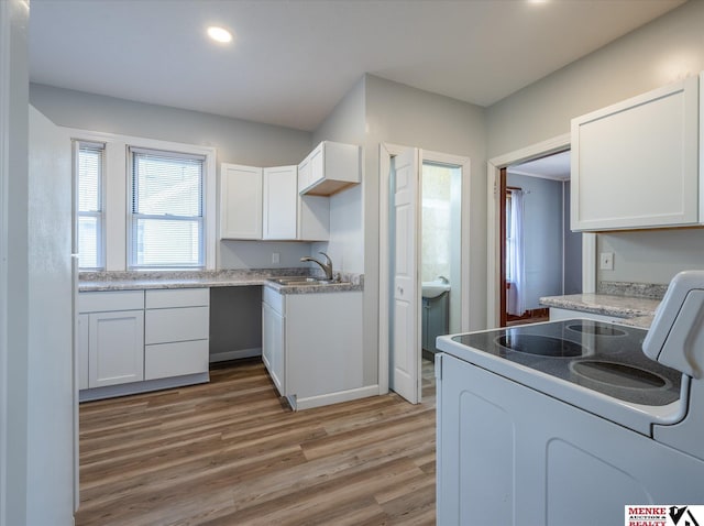 kitchen with range, hardwood / wood-style flooring, white cabinetry, and sink